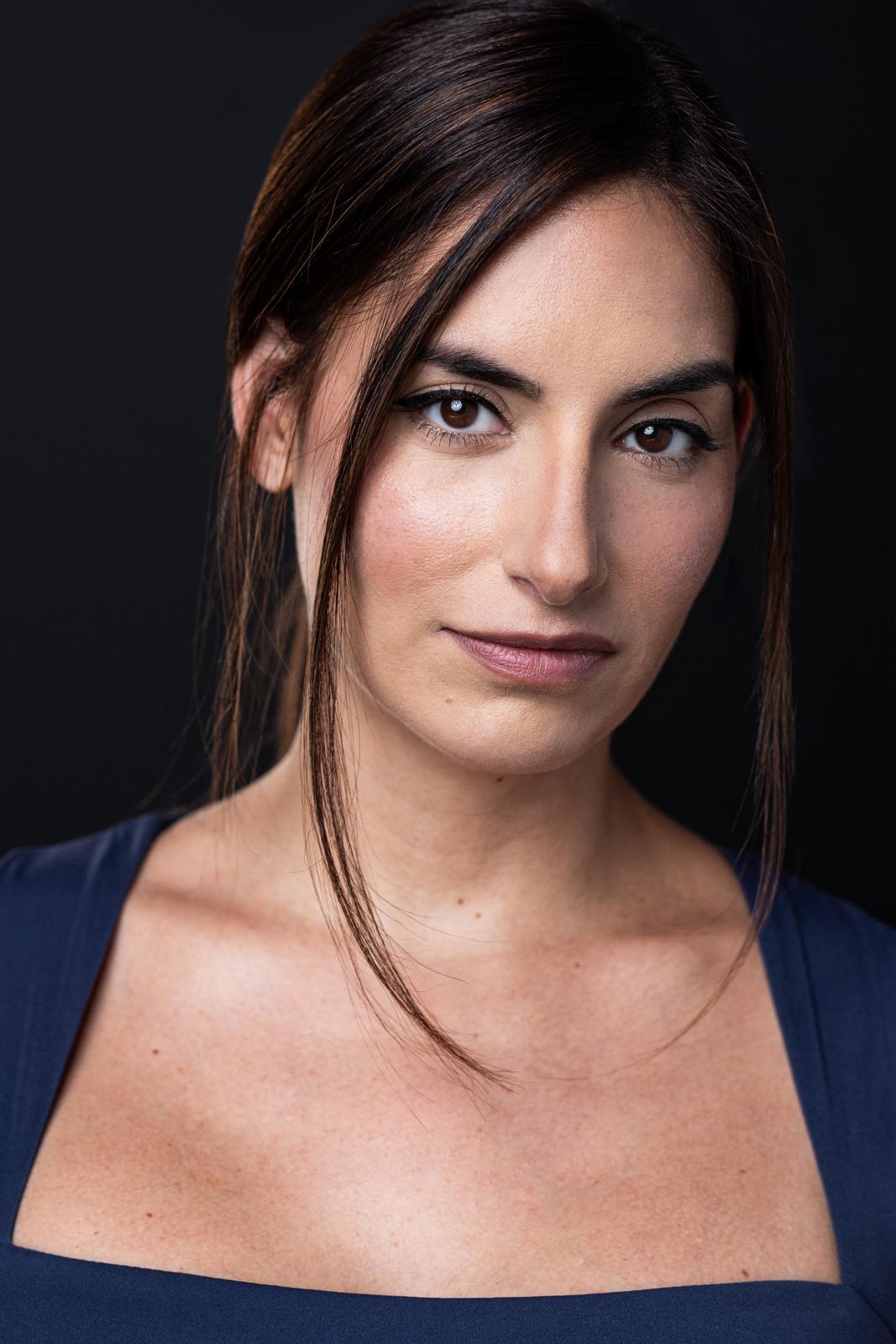 Maria Sky wearing navy blue in her acting headshot against a dark studio background